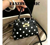 Ce sac à main en PU noir avec des accents de pois blancs présente une fermeture à verrou tournant, une seule poignée et une bandoulière réglable. Il est élégant et stylé, convenant aux femmes, aux étu