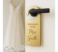 Décoration personnalisée de porte de mariée, annonce magnifiquement que la mariée se prépare pour son moment spécial, avec des symboles de mariage et un cadeau du matin de mariage suspendu à la poigné