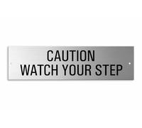 Panneau « Caution watch your step » 150 x 40 mm (2 trous pré-perforés)