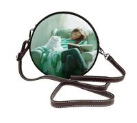 Sac à bandoulière rond en cuir pour femme avec livre de lecture sur fauteuil vert