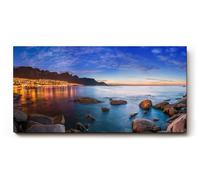Sinus Art Tableau mural 120 x 60 cm Scène du soir avec ville illuminée au bord de la mer, entourée de rochers et d'eau calme
