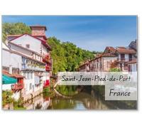 Vue panoramique de la ville française avec balcons rouges et fleurs traversées par une rivière tranquille. Saint-jean-pied-de-port, France, aimant frigo